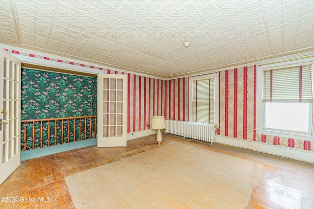 spare room featuring french doors, radiator heating unit, and wood-type flooring