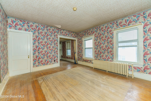 unfurnished room with radiator and wood-type flooring