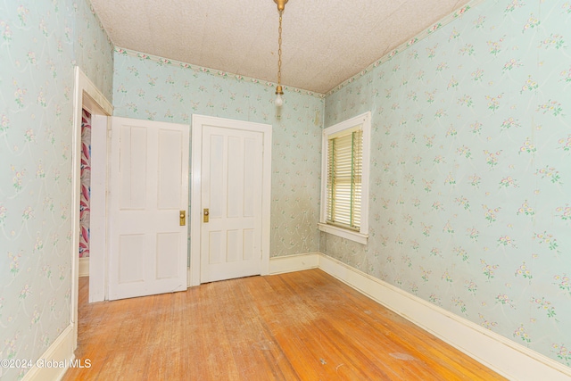 unfurnished room with a textured ceiling and hardwood / wood-style flooring