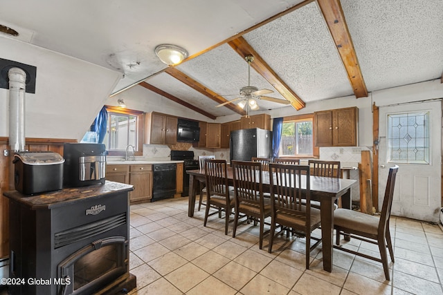 tiled dining area featuring lofted ceiling with beams, sink, ceiling fan, and a wood stove