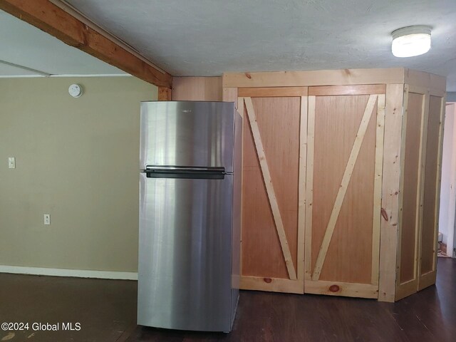 kitchen with light brown cabinetry, dark wood-type flooring, and stainless steel refrigerator