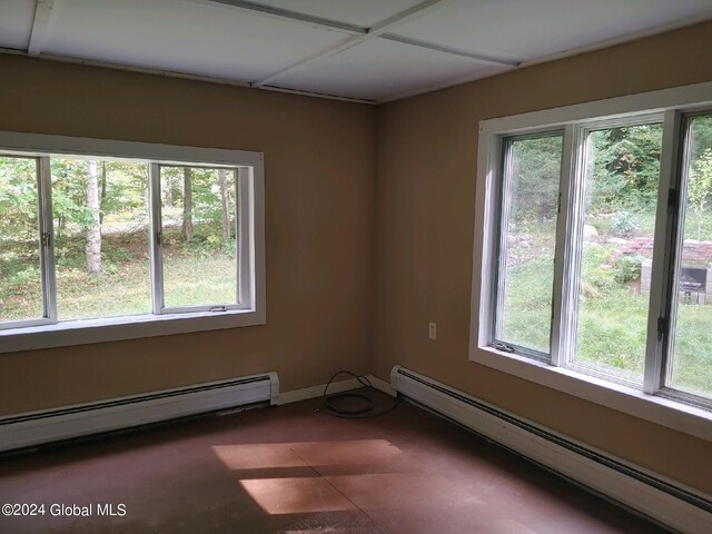 tiled empty room with a wealth of natural light and a baseboard heating unit