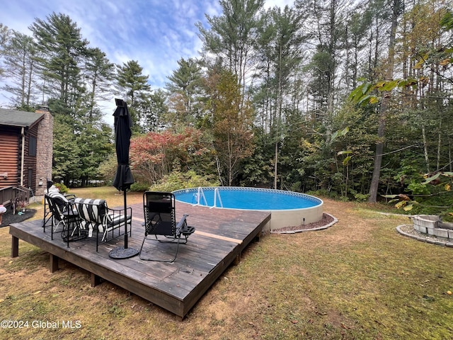 view of pool featuring a lawn and a wooden deck