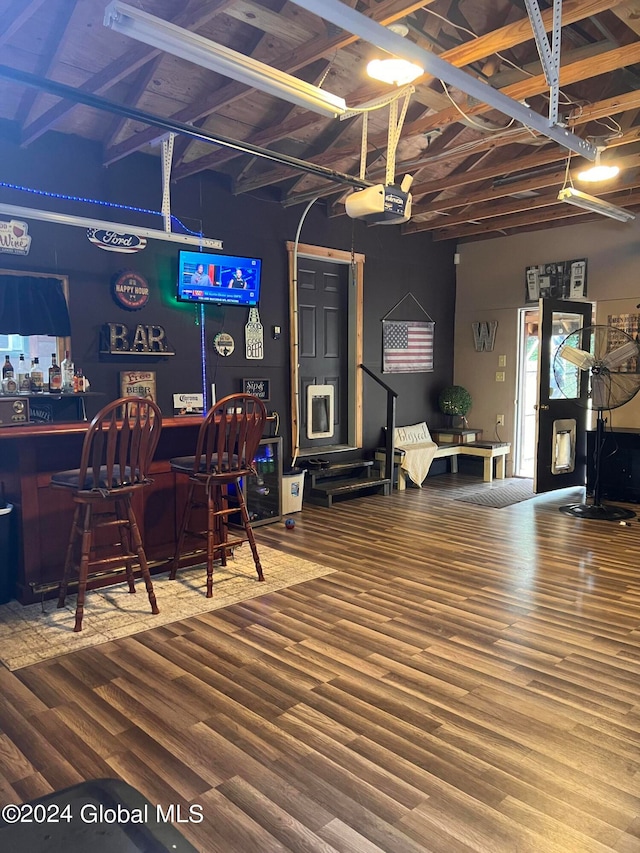 miscellaneous room featuring wood-type flooring, bar, and a towering ceiling