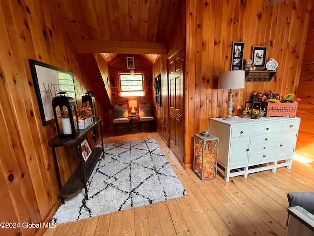 foyer entrance featuring light wood-type flooring, wooden walls, and beamed ceiling