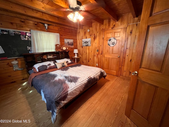 bedroom featuring beam ceiling, light hardwood / wood-style floors, wood walls, and wooden ceiling