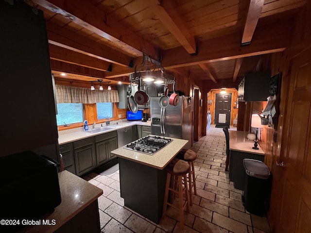 kitchen with appliances with stainless steel finishes, a breakfast bar, beam ceiling, a center island, and wooden walls