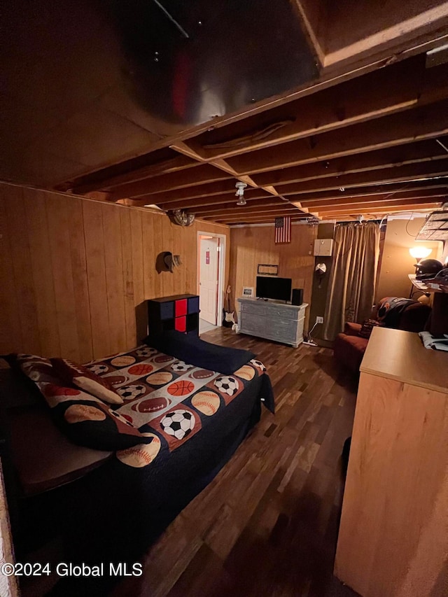 bedroom featuring wooden walls and dark hardwood / wood-style flooring