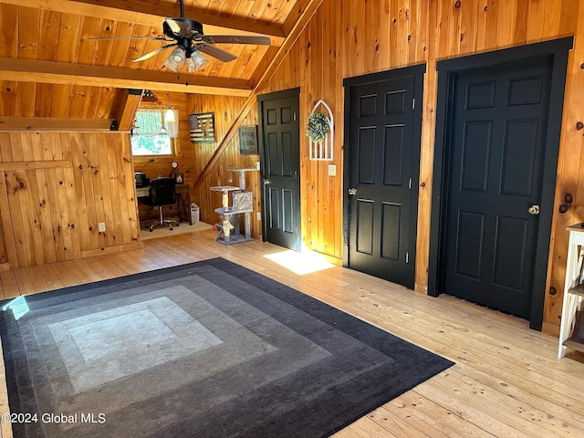 foyer featuring wood ceiling, wood walls, ceiling fan, light hardwood / wood-style flooring, and vaulted ceiling with beams