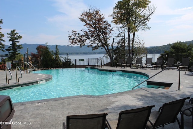 view of swimming pool featuring a patio and a water and mountain view