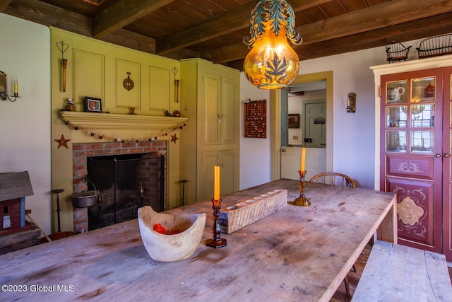 dining room with wood ceiling, a brick fireplace, and beam ceiling