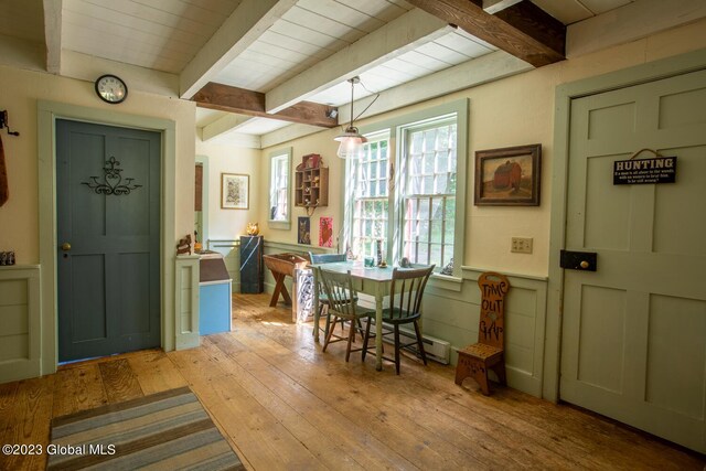 dining room featuring beamed ceiling and light hardwood / wood-style flooring