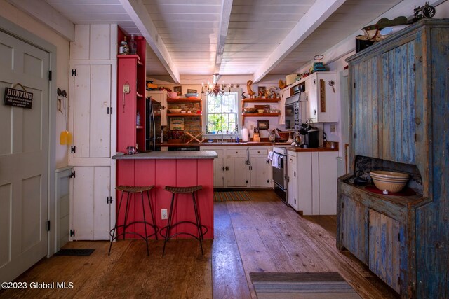 kitchen with a kitchen breakfast bar, white cabinetry, kitchen peninsula, light hardwood / wood-style flooring, and sink