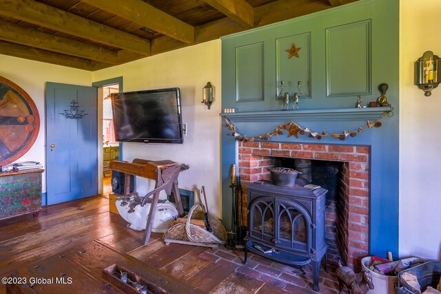 living room with a fireplace, a wood stove, wooden ceiling, beam ceiling, and dark hardwood / wood-style floors