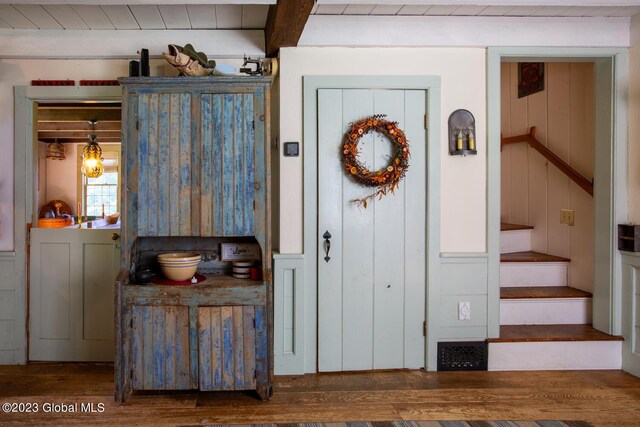 entrance foyer with wooden walls, beam ceiling, and dark hardwood / wood-style flooring