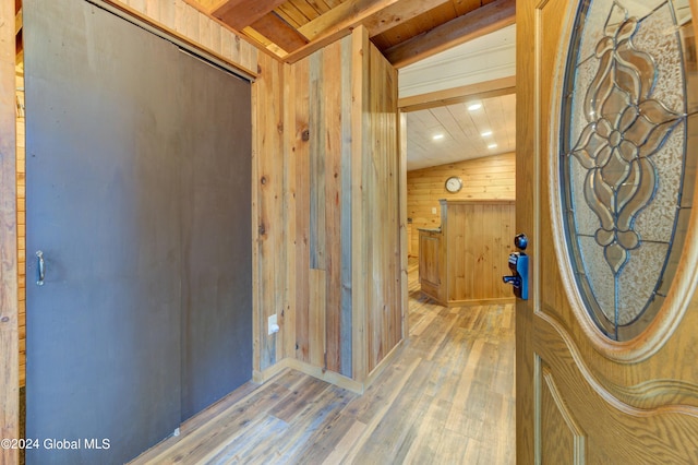 hall featuring lofted ceiling with beams, wooden walls, wood-type flooring, and wooden ceiling