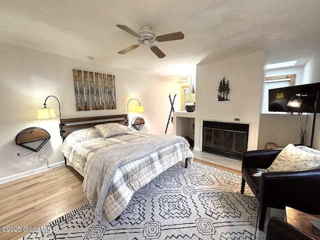 13 Freebern Rd Unit E, Johnsburg, NY 12853 - bedroom with wood finished floors, baseboards, a fireplace with flush hearth, and a ceiling fan