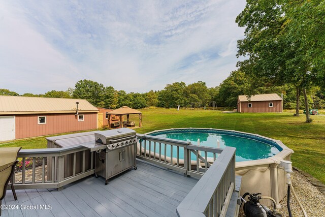 view of swimming pool featuring a deck, area for grilling, a shed, and a yard