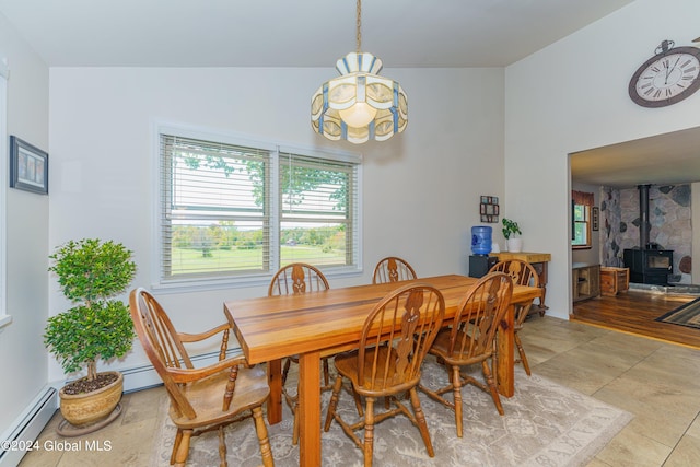 tiled dining space featuring lofted ceiling, a wood stove, and a baseboard radiator