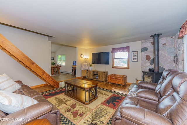 living room featuring plenty of natural light, a baseboard radiator, a wood stove, and hardwood / wood-style flooring