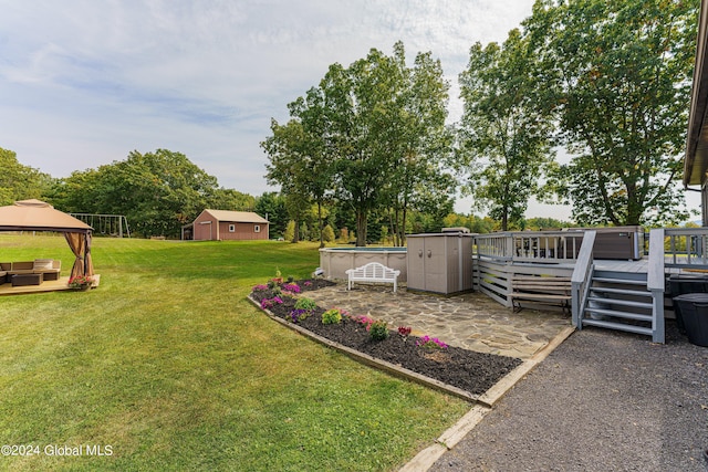 view of yard featuring a gazebo, a storage shed, a wooden deck, and a patio