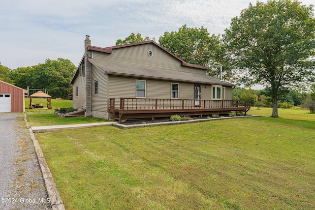 back of property with a lawn, an outbuilding, a deck, and a garage