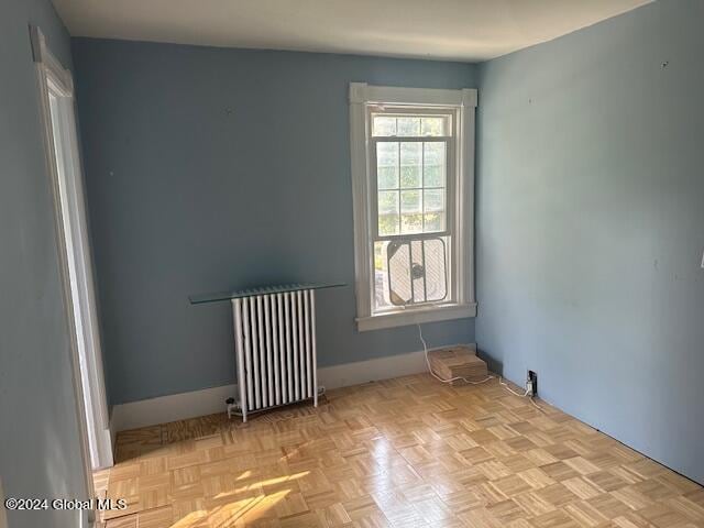 spare room with radiator heating unit and light parquet flooring