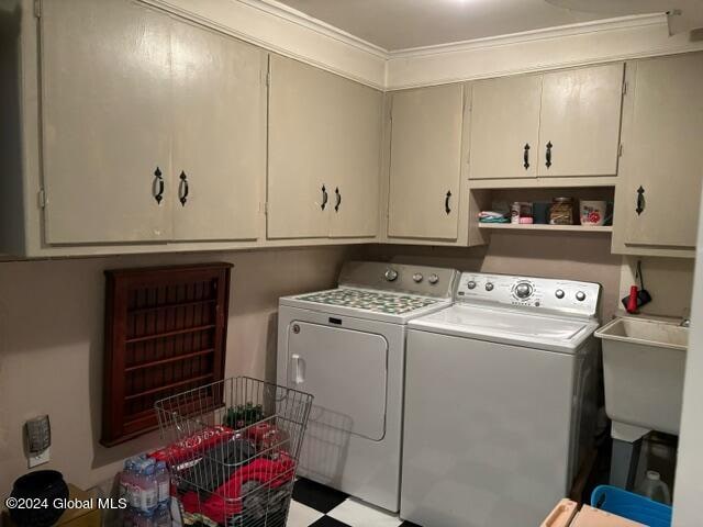 clothes washing area with cabinets, washing machine and dryer, ornamental molding, and sink