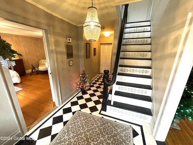 staircase with wood walls, ornamental molding, and a chandelier