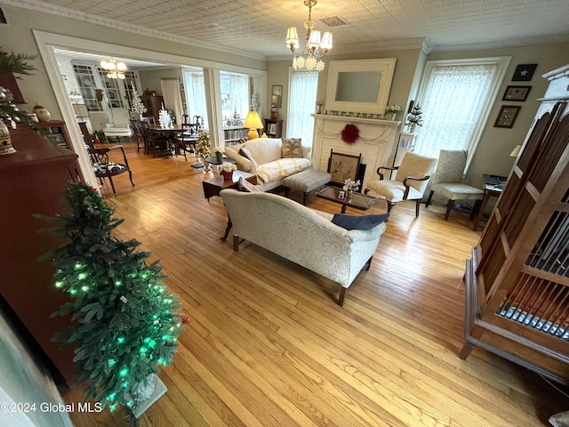living room featuring ornamental molding, a fireplace, light hardwood / wood-style floors, and a notable chandelier