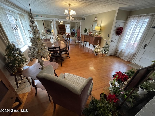living room with hardwood / wood-style floors, ornamental molding, and an inviting chandelier