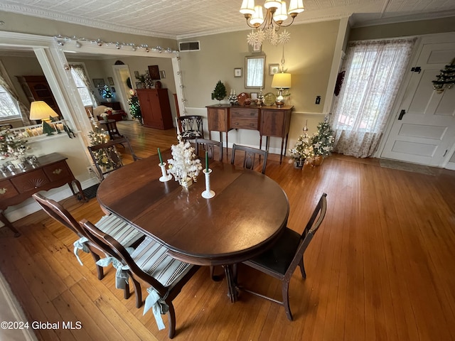 dining space featuring hardwood / wood-style flooring, an inviting chandelier, and crown molding