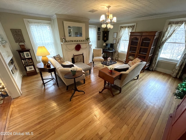 living area featuring a notable chandelier, a fireplace, light hardwood / wood-style floors, and crown molding