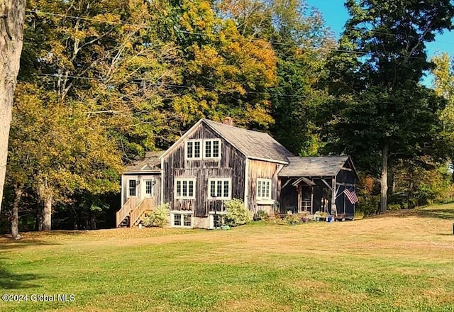 view of front of house featuring stairway, a front lawn, and a view of trees