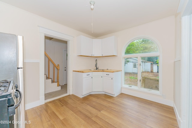 kitchen with butcher block countertops, stainless steel range, light hardwood / wood-style floors, and white cabinetry