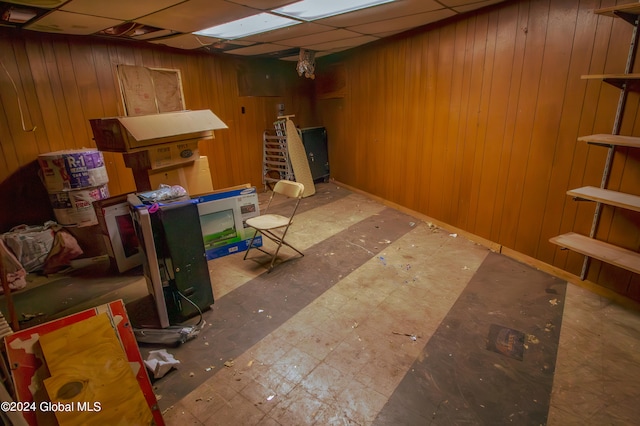 basement featuring wood walls and a paneled ceiling