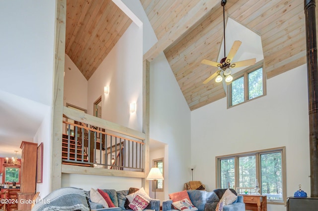 living room with wooden ceiling, ceiling fan with notable chandelier, beam ceiling, and high vaulted ceiling