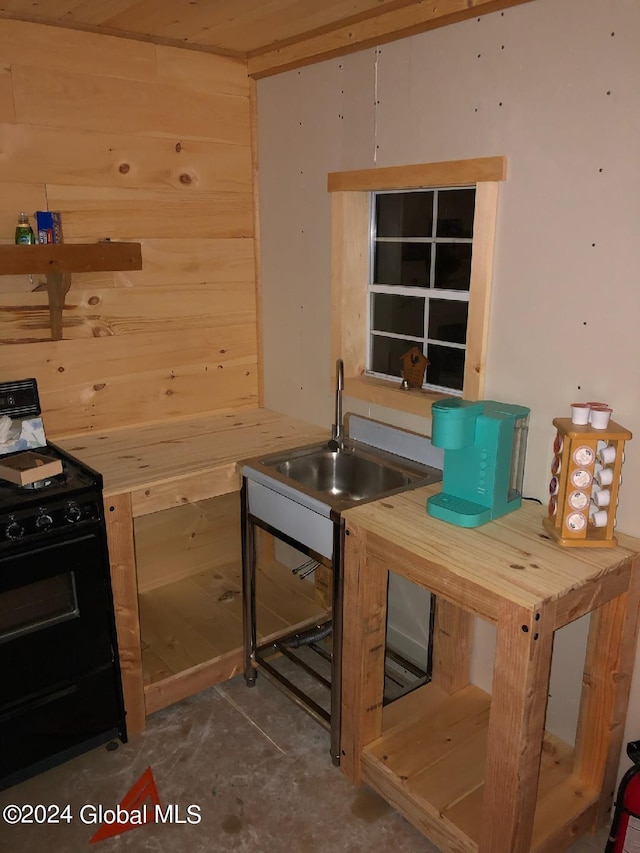 kitchen with black range with electric cooktop, sink, and wooden walls