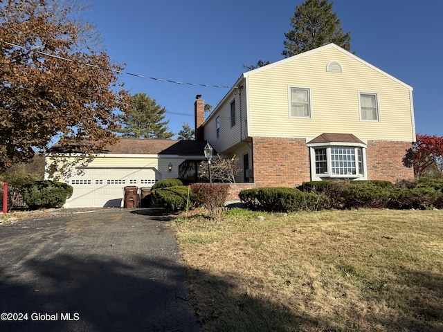 25 Kling Ter, Voorheesville, NY 12186 - view of front facade with brick siding, asphalt driveway, a garage, a chimney, and a front lawn