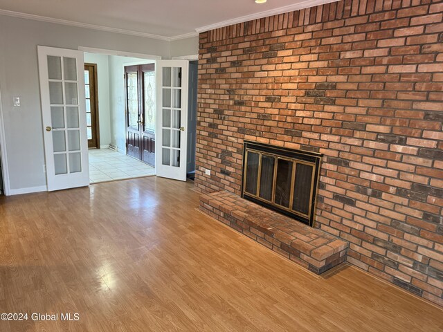 25 Kling Ter, Voorheesville, NY 12186 - unfurnished living room featuring french doors, a brick fireplace, wood finished floors, baseboards, and crown molding