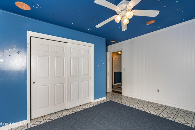 unfurnished bedroom with ceiling fan and a closet