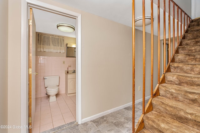 stairs featuring tile patterned flooring and tile walls