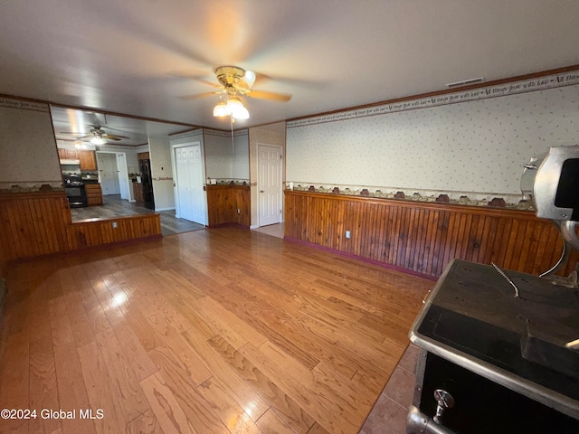 unfurnished living room with ceiling fan, ornamental molding, and light hardwood / wood-style flooring