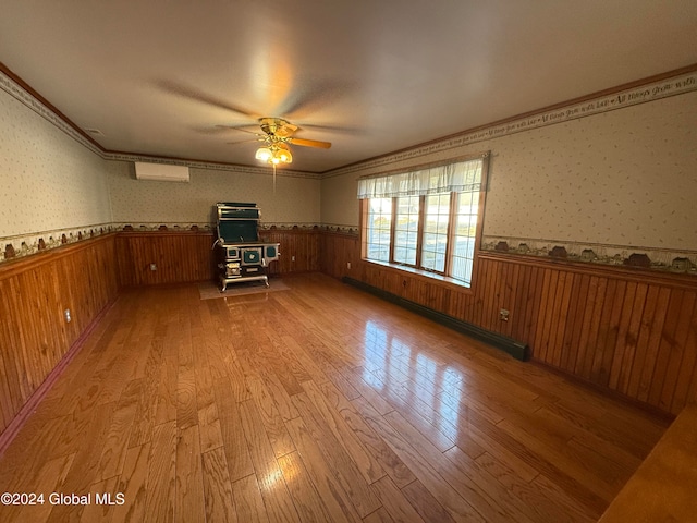 empty room with light hardwood / wood-style floors, an AC wall unit, baseboard heating, and ceiling fan