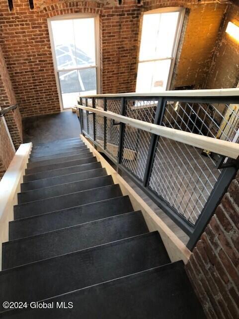 staircase featuring brick wall, a high ceiling, and a wealth of natural light