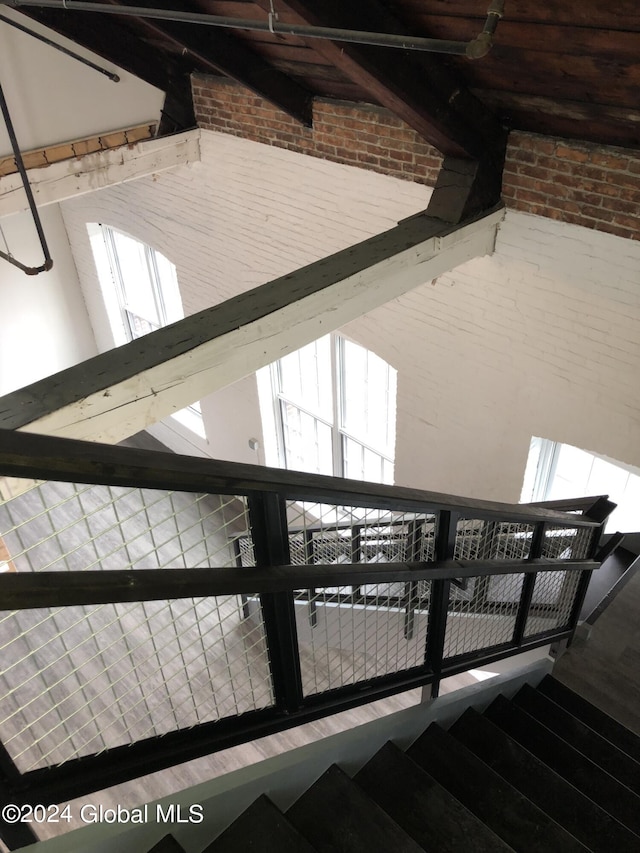 staircase featuring brick wall, hardwood / wood-style floors, and a high ceiling