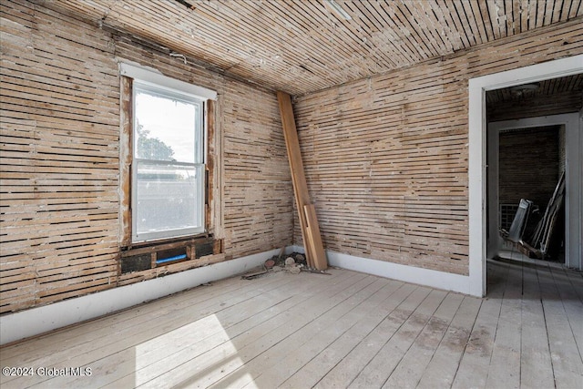 empty room featuring light wood-type flooring and wooden walls