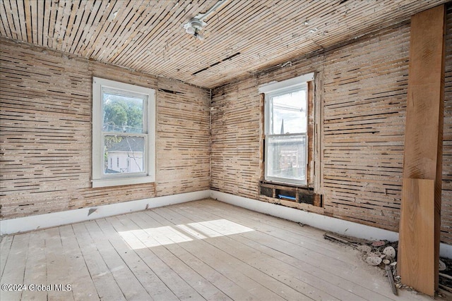 unfurnished room with light hardwood / wood-style floors and wooden walls