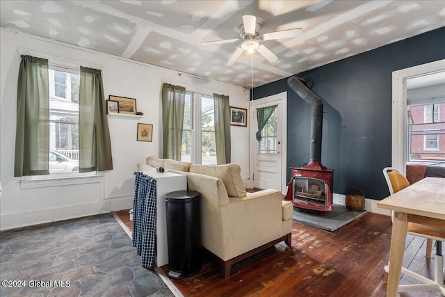 living room featuring a wood stove, plenty of natural light, ceiling fan, and dark hardwood / wood-style floors