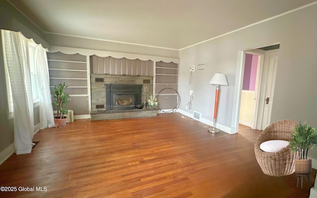 unfurnished living room featuring wood finished floors, baseboards, and a stone fireplace